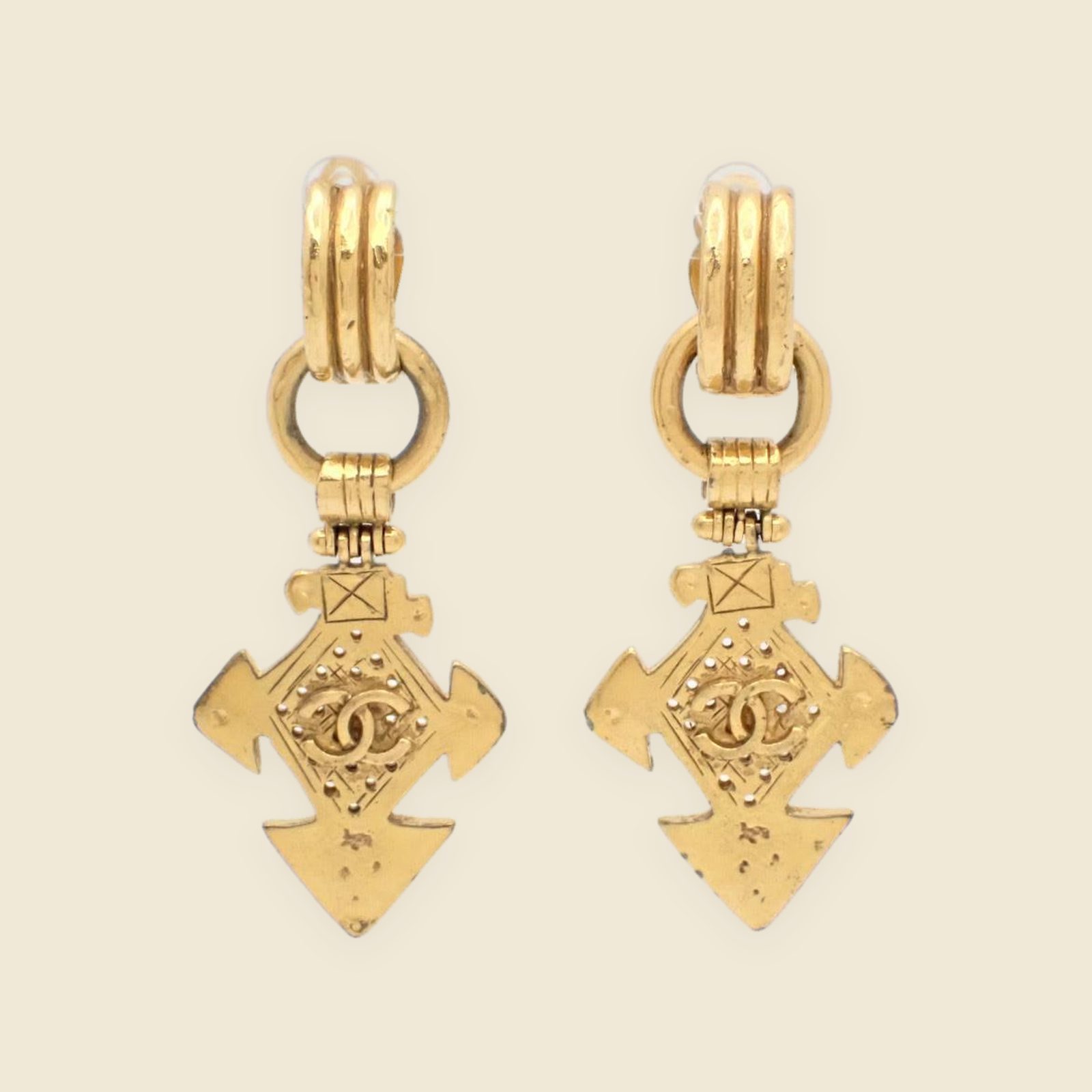 Orecchini a clip Chanel pendenti in metallo dorato, placca a croce con logo CC al centro, vista frontale