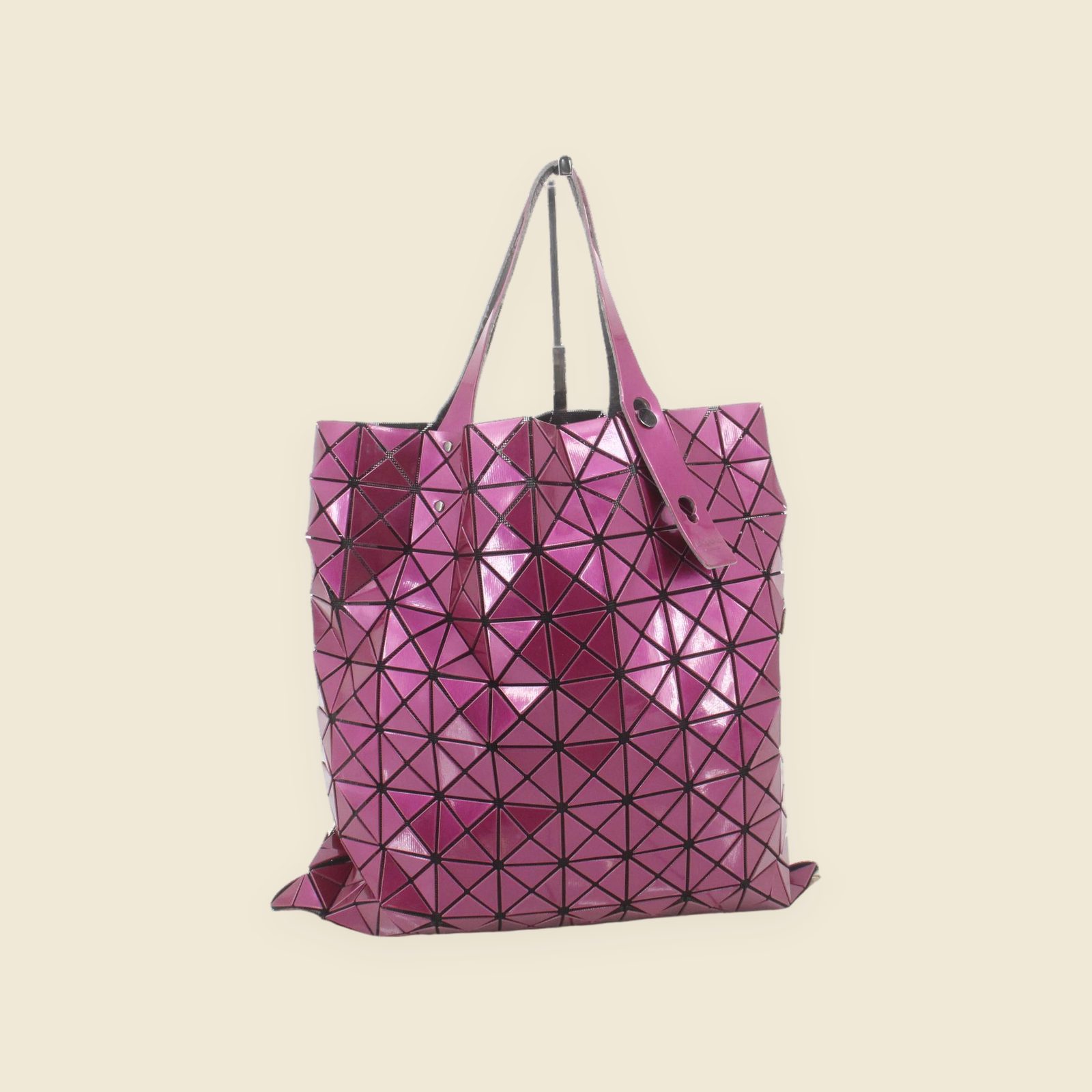 Borsa tote Issey Miyake magenta in PVC lucido, con pannelli triangolari e due manici, vista frontale su fondo bianco