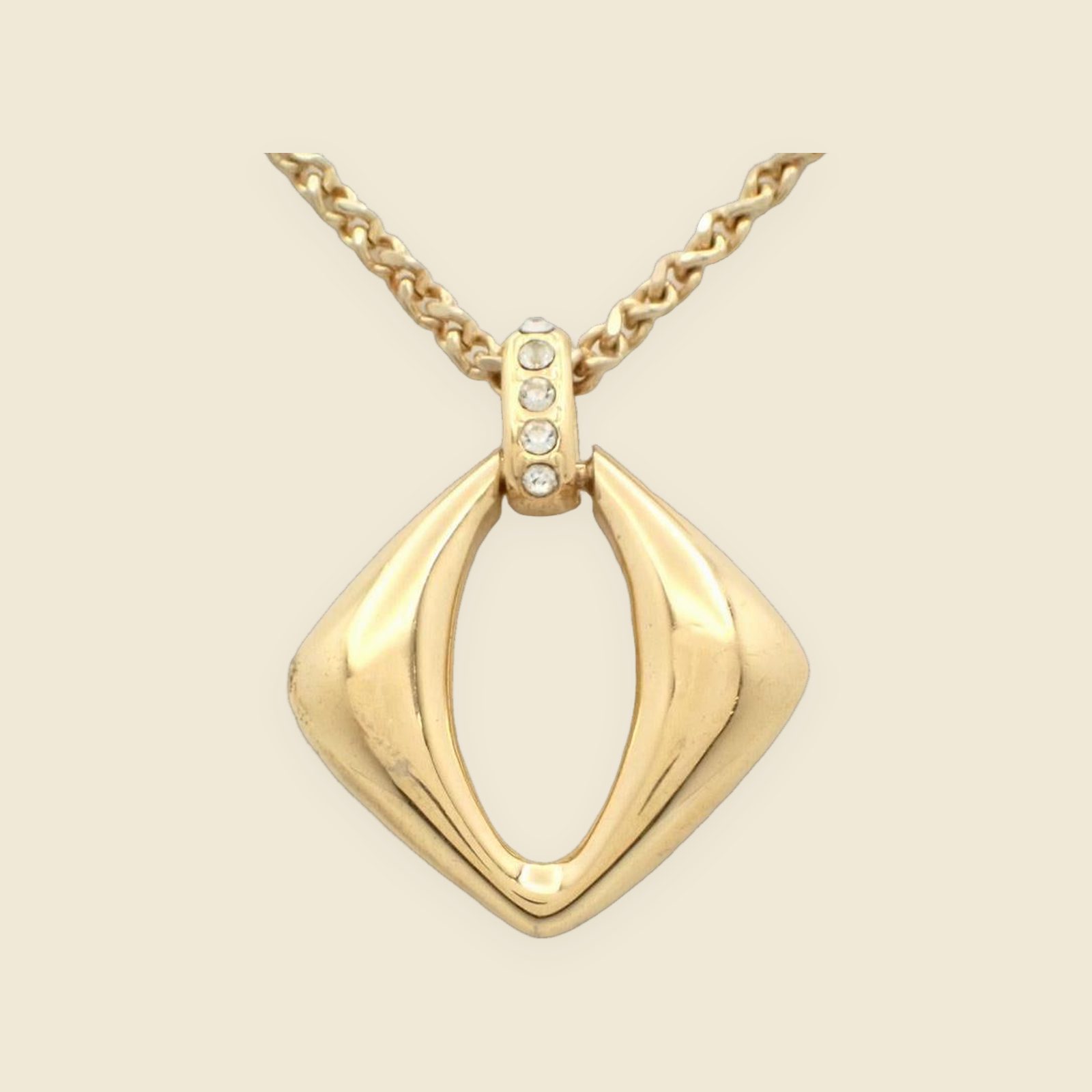 Collana Yves Saint Laurent in metallo dorato con pendente a losanga traforata e strass, vista su busto espositore