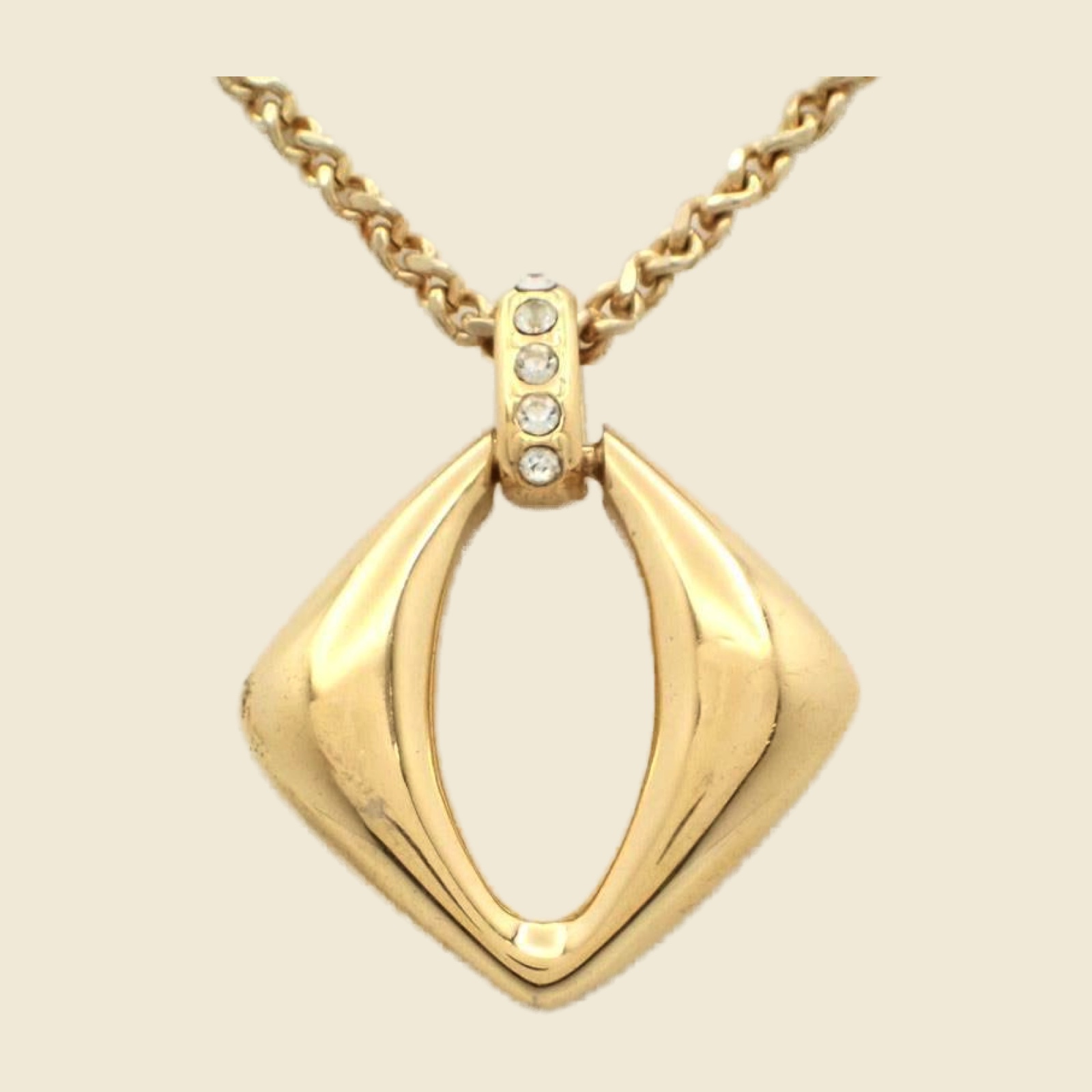 Collana Yves Saint Laurent in metallo dorato con pendente a losanga traforata e strass, vista su busto espositore