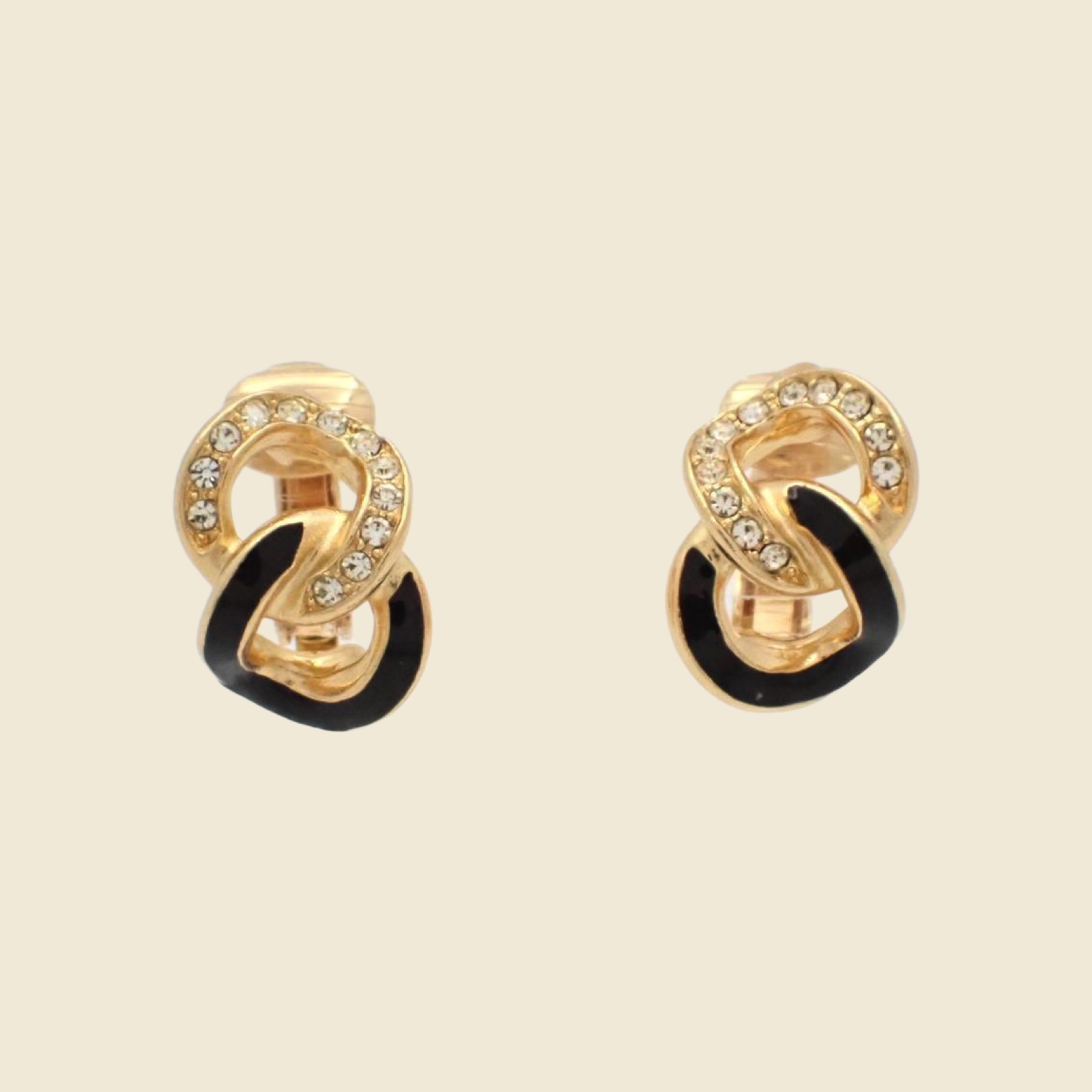 Orecchini a clip Christian Dior in metallo dorato a nodo intrecciato, con smalto nero e strass, su fondo chiaro