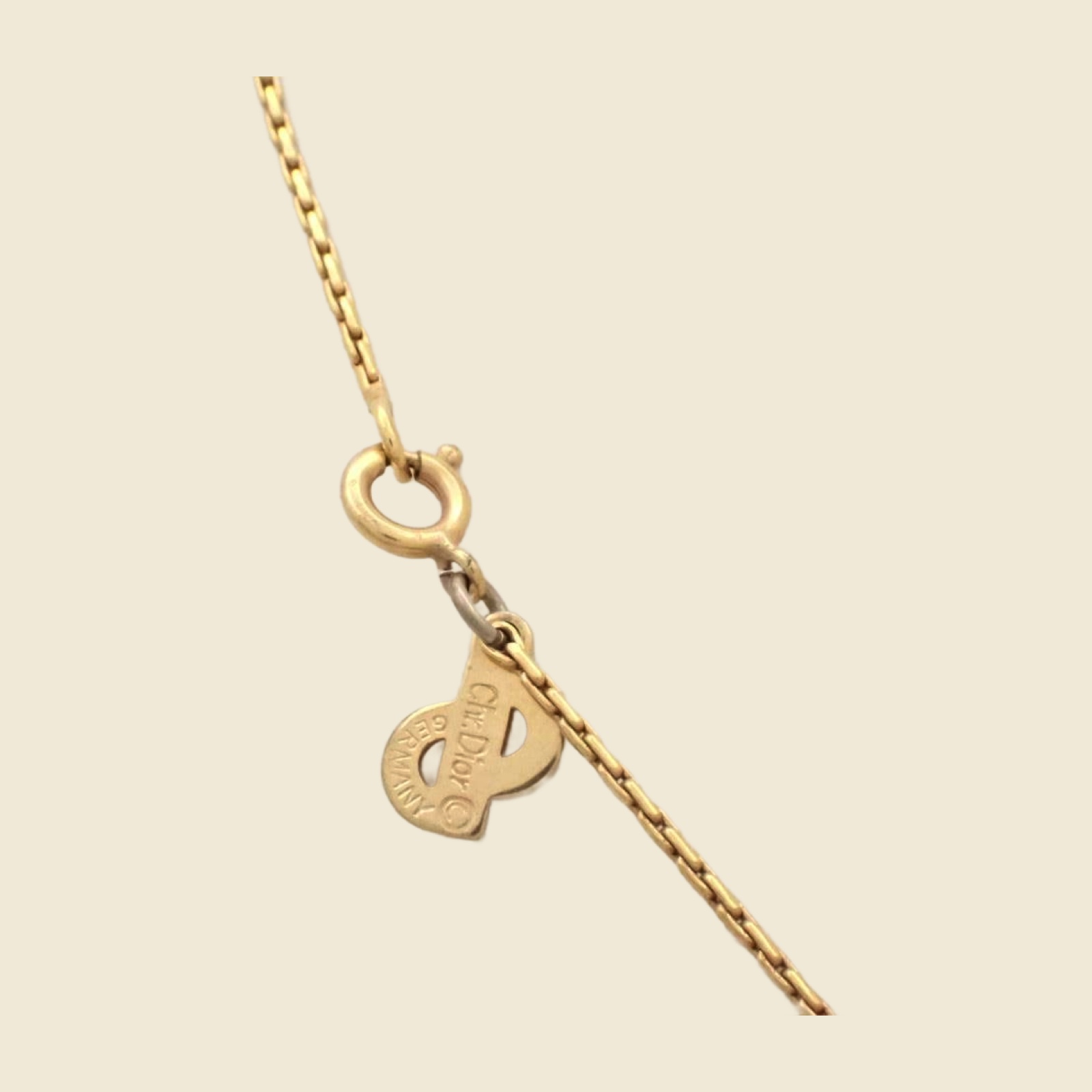 Collana Christian Dior in metallo dorato con pendente arcuato a pietre chiare e catena sottile, su fondo neutro — vista 2