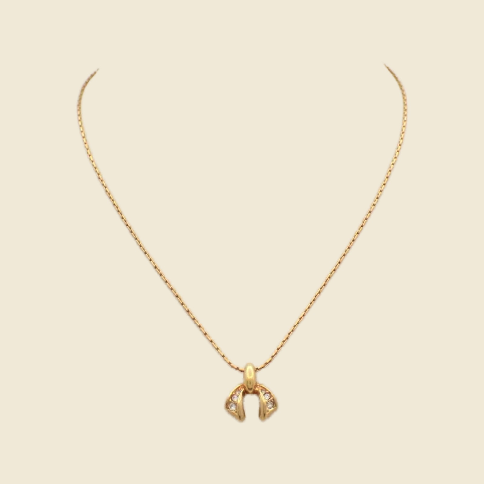 Collana Christian Dior in metallo dorato con pendente arcuato a pietre chiare e catena sottile, su fondo neutro — vista 3