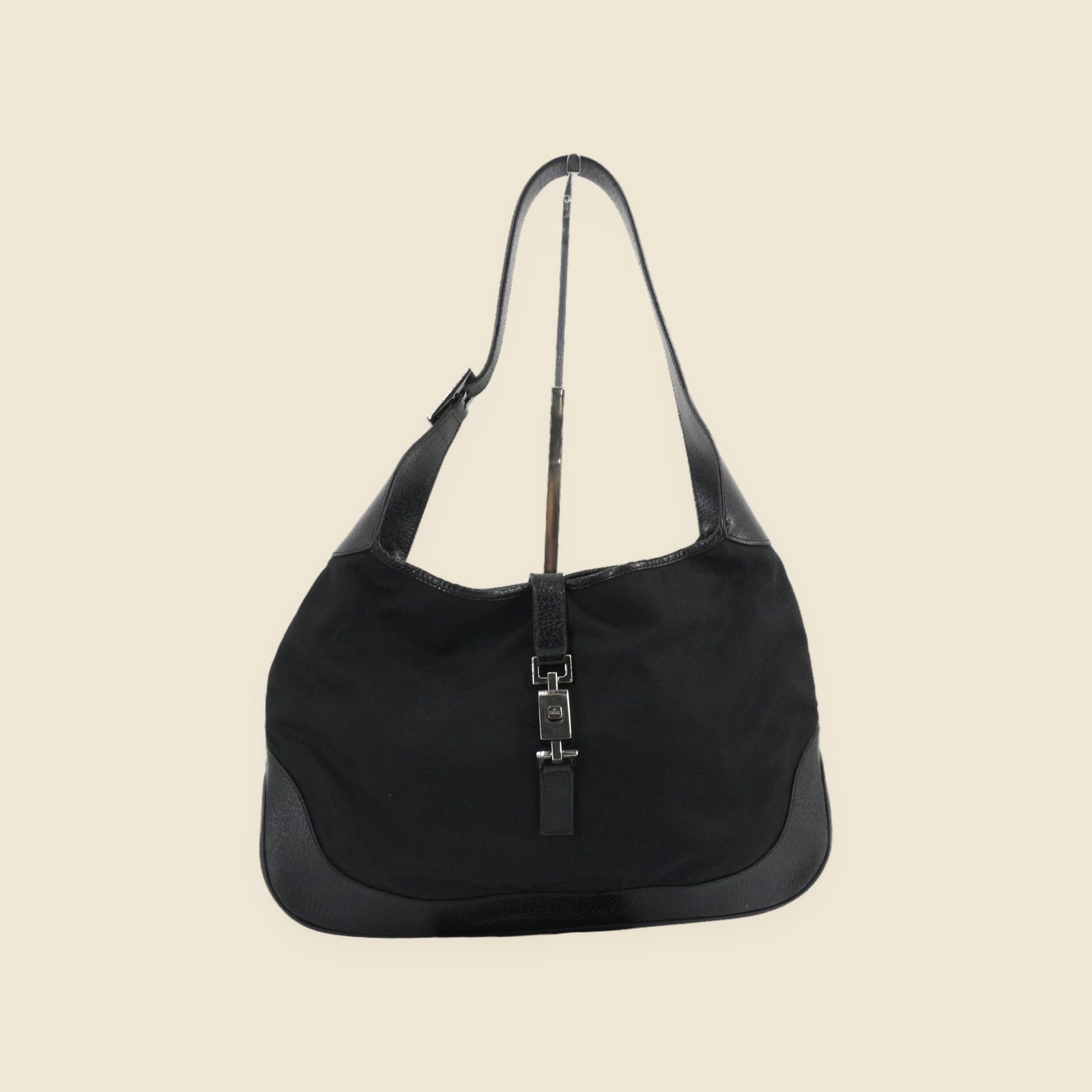 Borsa a spalla Gucci in tela nera con inserti in pelle e chiusura a pistone argentata, vista frontale su fondo bianco