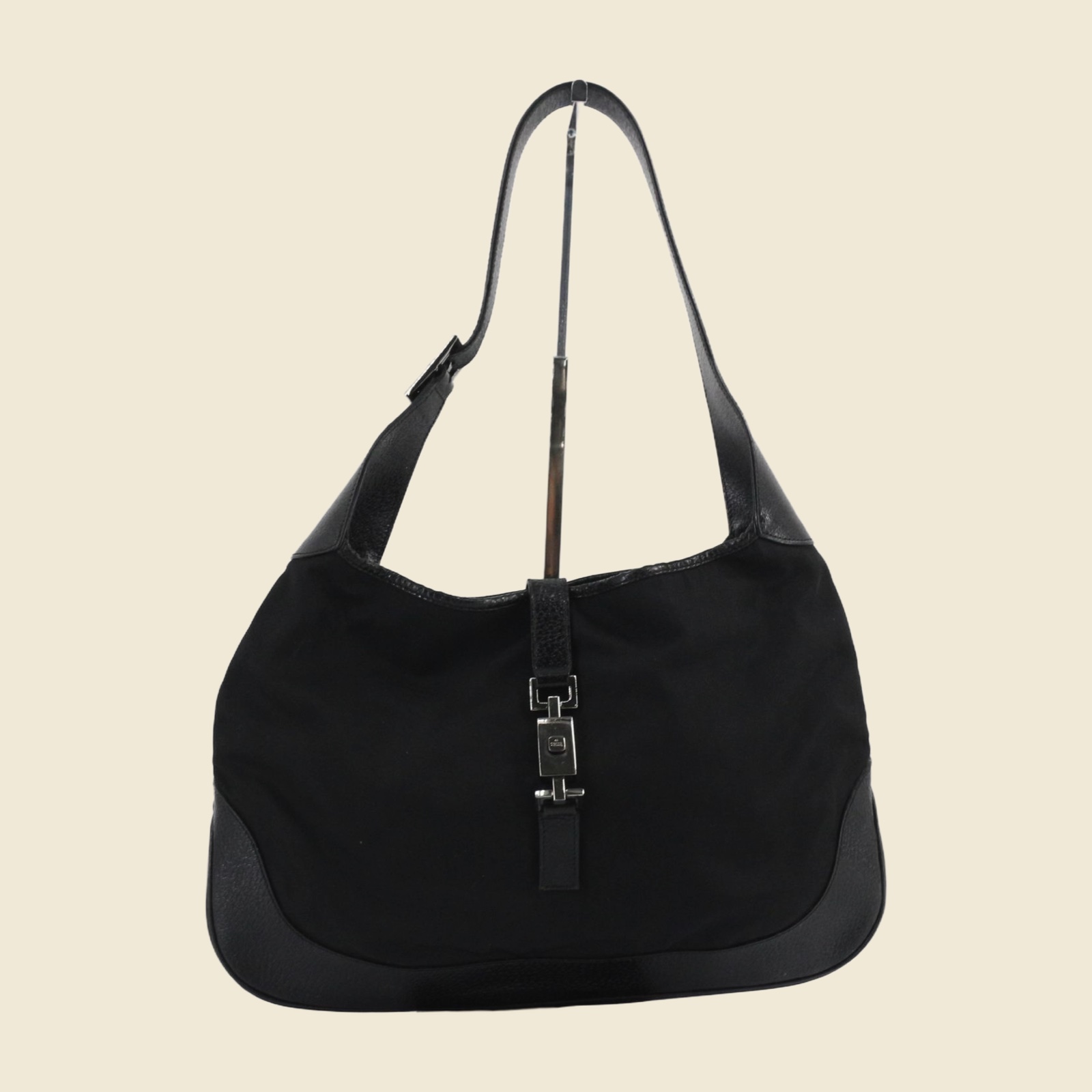 Borsa a spalla Gucci in tela nera con inserti in pelle e chiusura a pistone argentata, vista frontale su fondo bianco