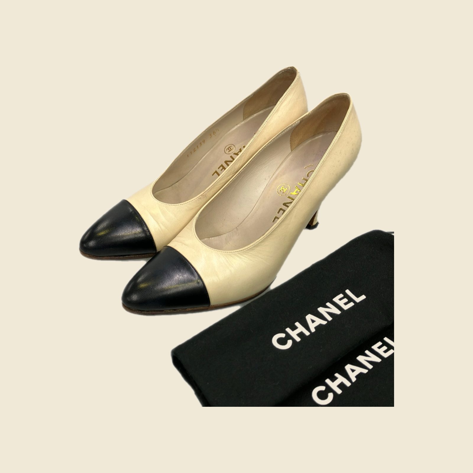 Décolleté Chanel in pelle avorio con punta nera e tacco alto, vista di tre quarti su fondo neutro
