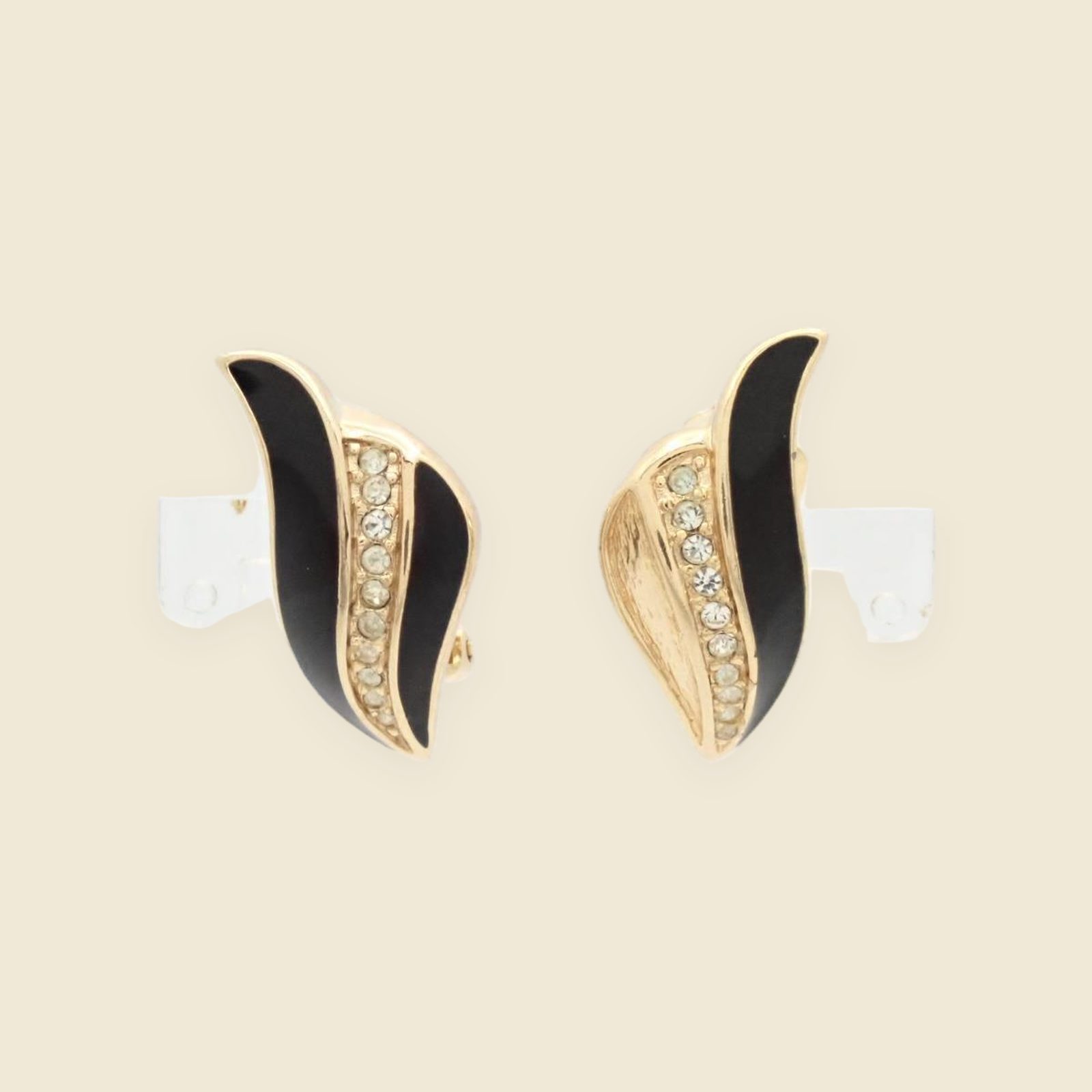Paio di orecchini a clip Christian Dior in metallo dorato, smalto nero e strass, su fondo neutro