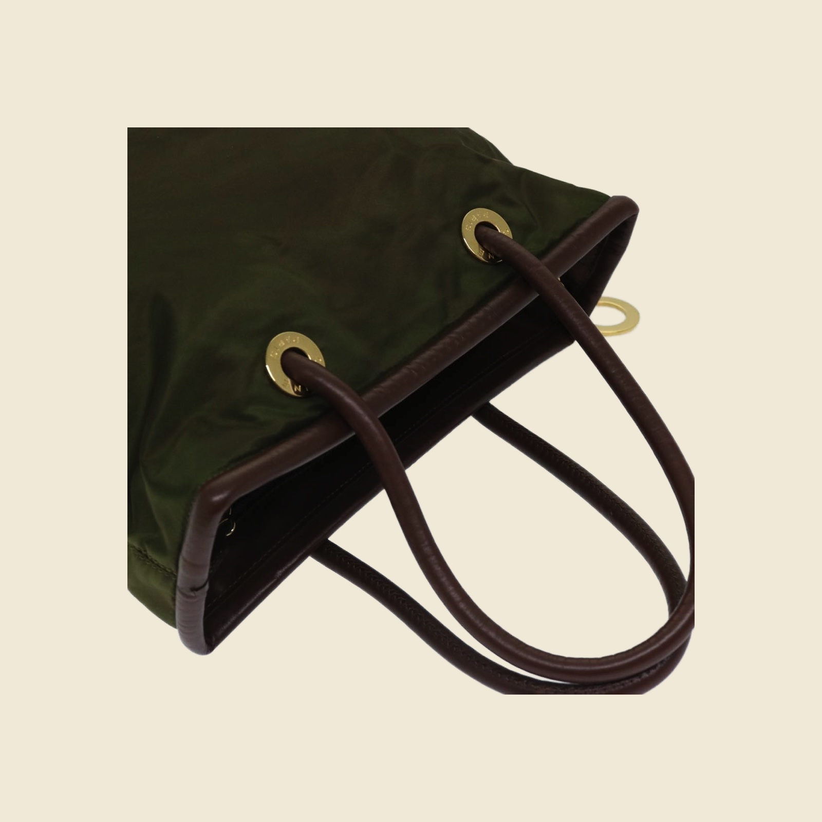 Borsa a mano Celine in tessuto verde oliva con manici in pelle marrone e anelli dorati, vista di tre quarti su fondo bianco — vista 2