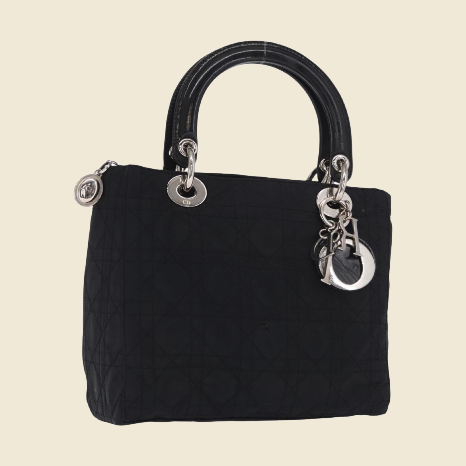 Borsa a mano Christian Dior in nylon nero trapuntato Cannage, doppio manico e ciondoli argentati, vista di tre quarti su fondo bianco