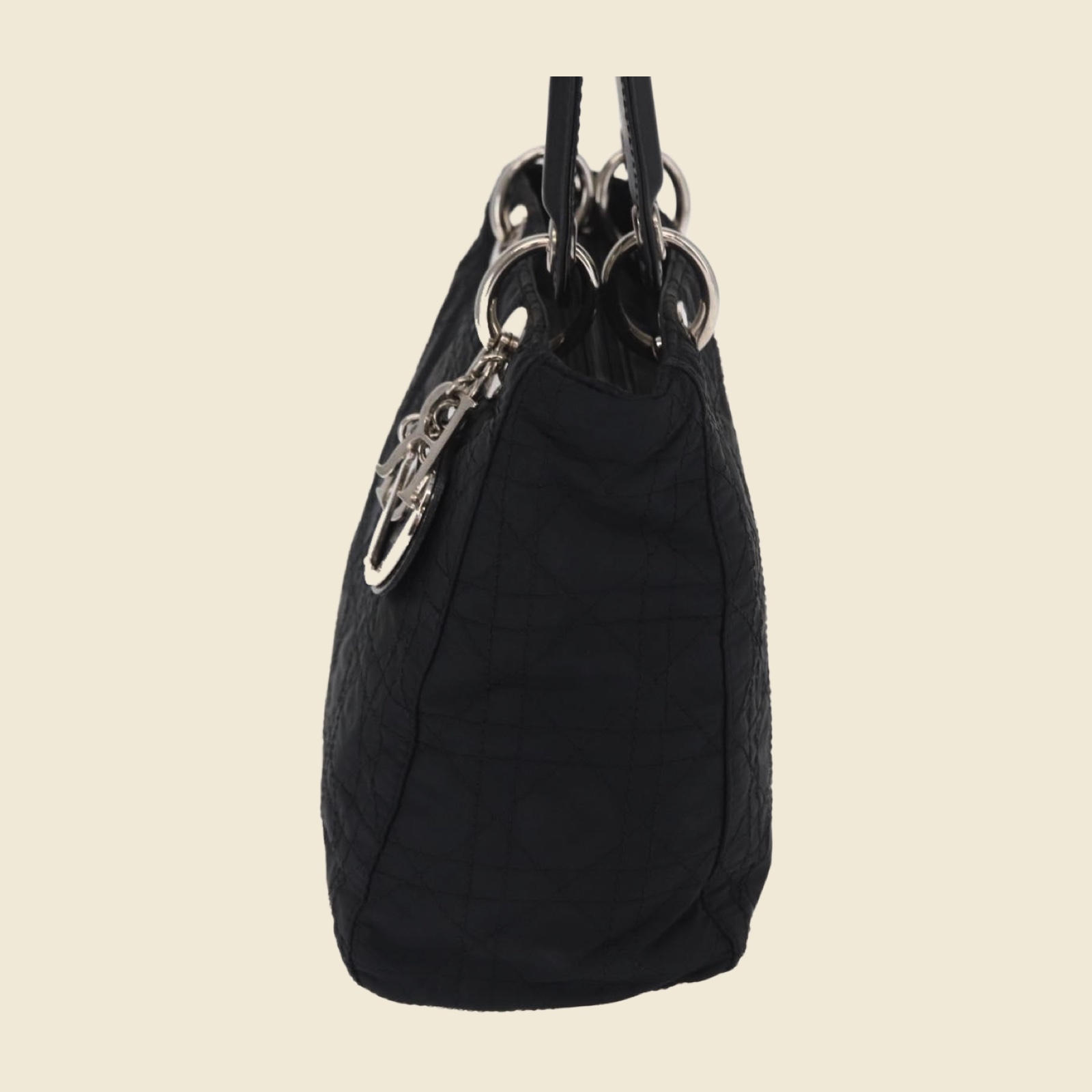 Borsa a mano Christian Dior in nylon nero trapuntato Cannage, doppio manico e ciondoli argentati, vista di tre quarti su fondo bianco — vista 3