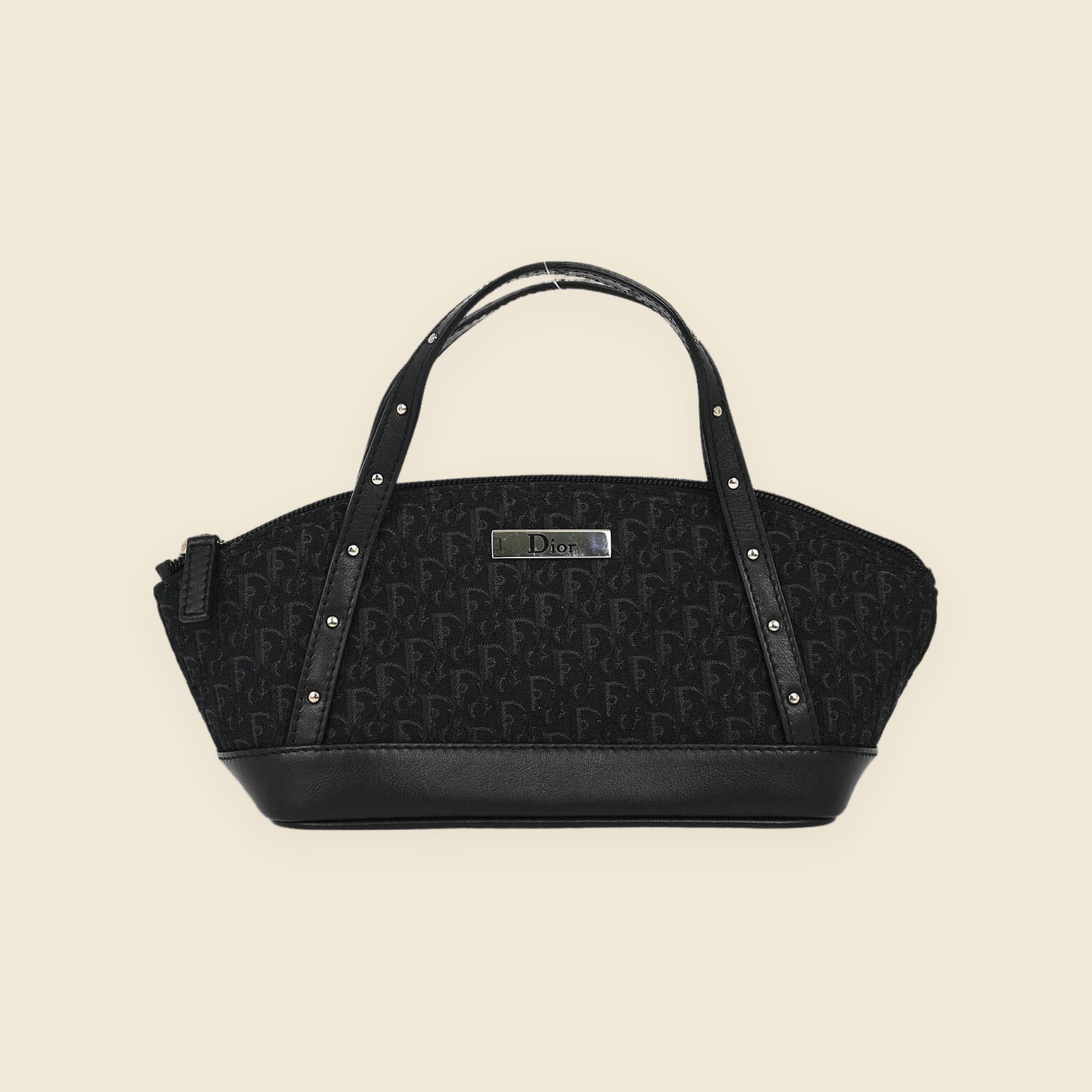 Borsa a mano Christian Dior in tela monogram nera e pelle, doppi manici con borchie argentate, vista frontale su fondo bianco