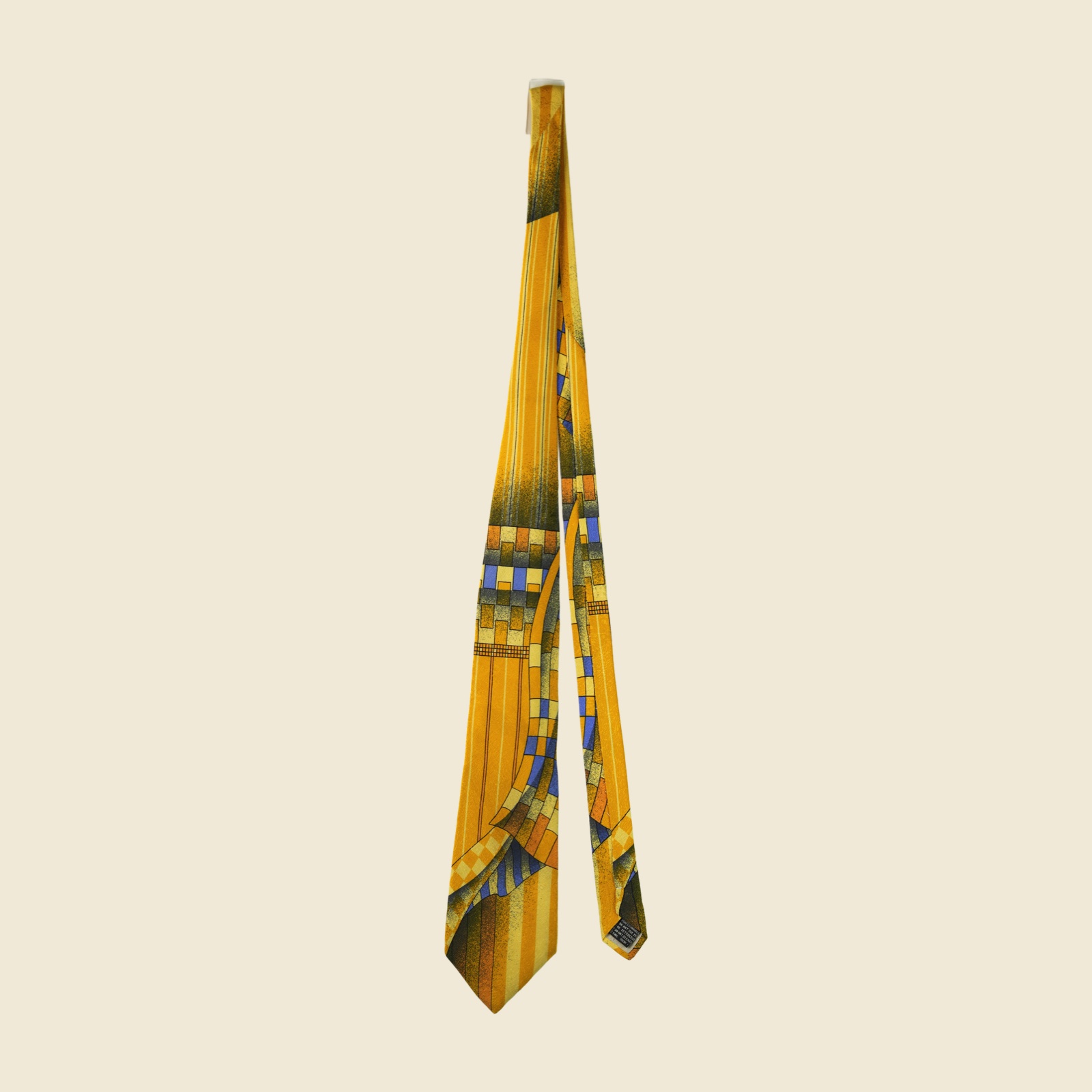 Cravatta Gianni Versace in seta giallo senape con stampa geometrica astratta blu e ruggine, su fondo bianco