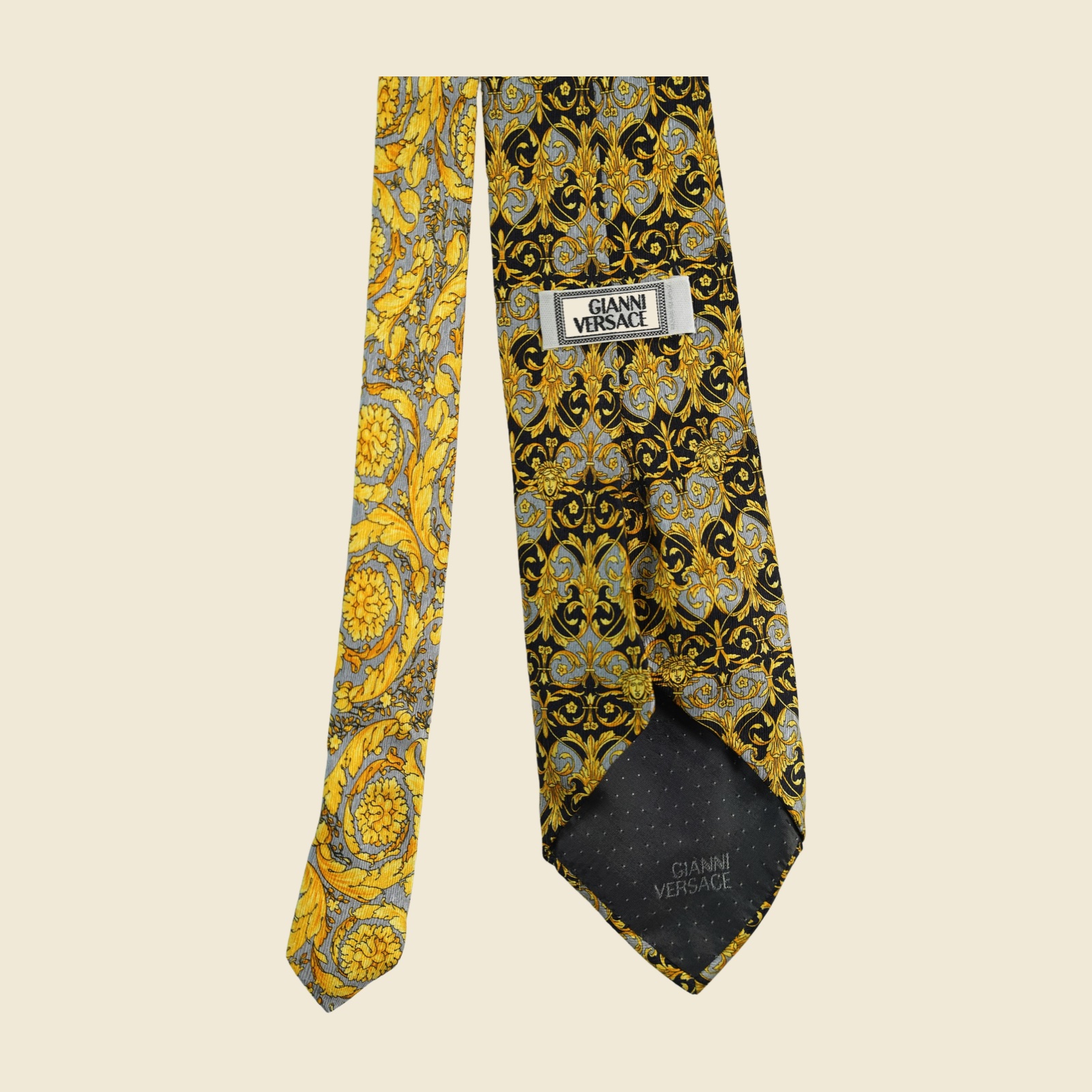 Cravatta Gianni Versace barocca a pannello, volute d'acanto e mascheroni in oro su fondo nero e grigio argento, vista frontale su fondo neutro — vista 2
