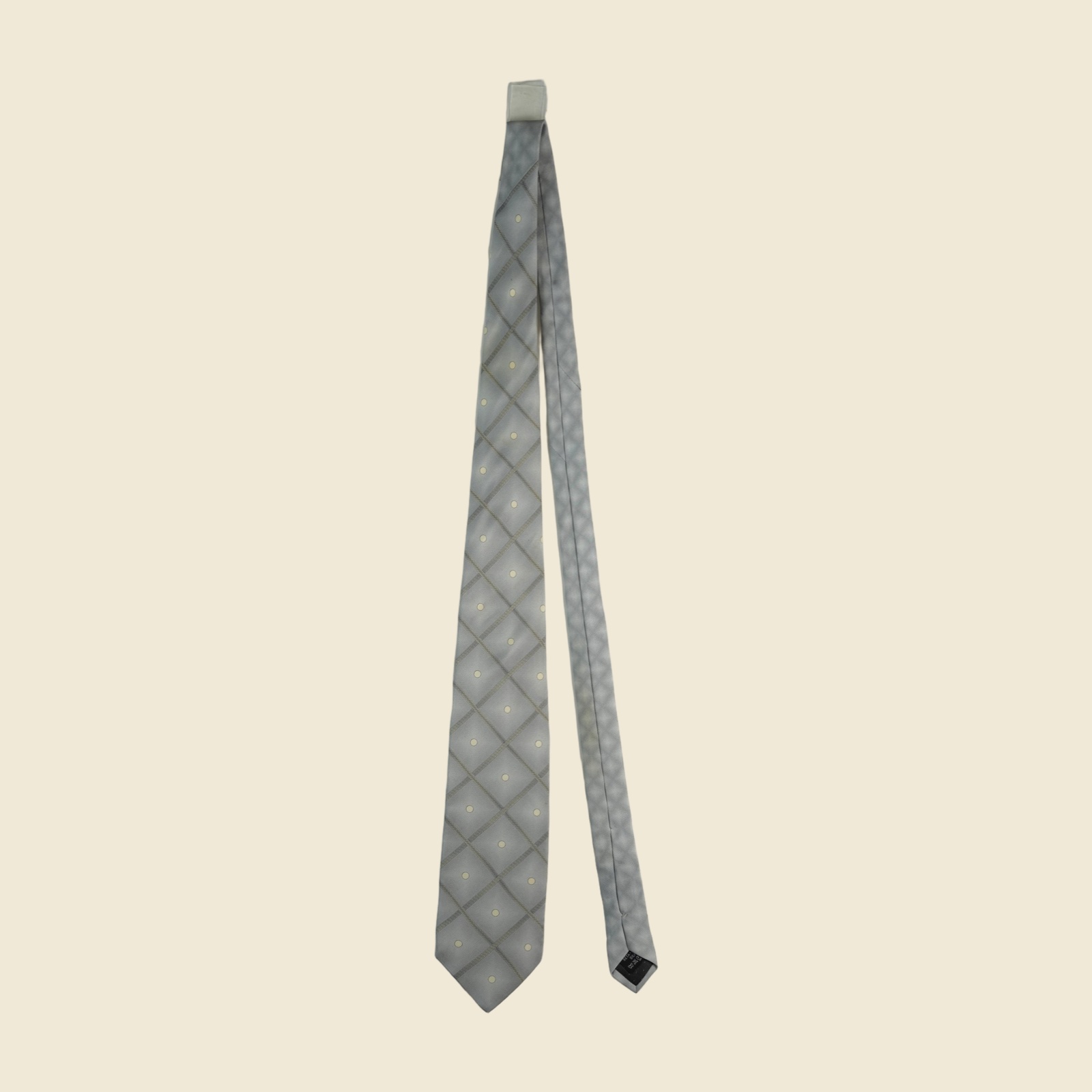 Cravatta Gianni Versace in seta grigio argento, reticolo diagonale di greca a rombi con pois avorio, su fondo neutro