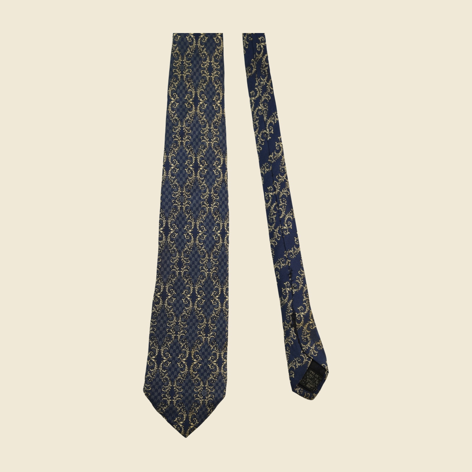 Cravatta Gianni Versace in seta blu navy con tralci d'acanto e volute avorio-oro a fasce diagonali, vista intera in posa piatta — vista 2