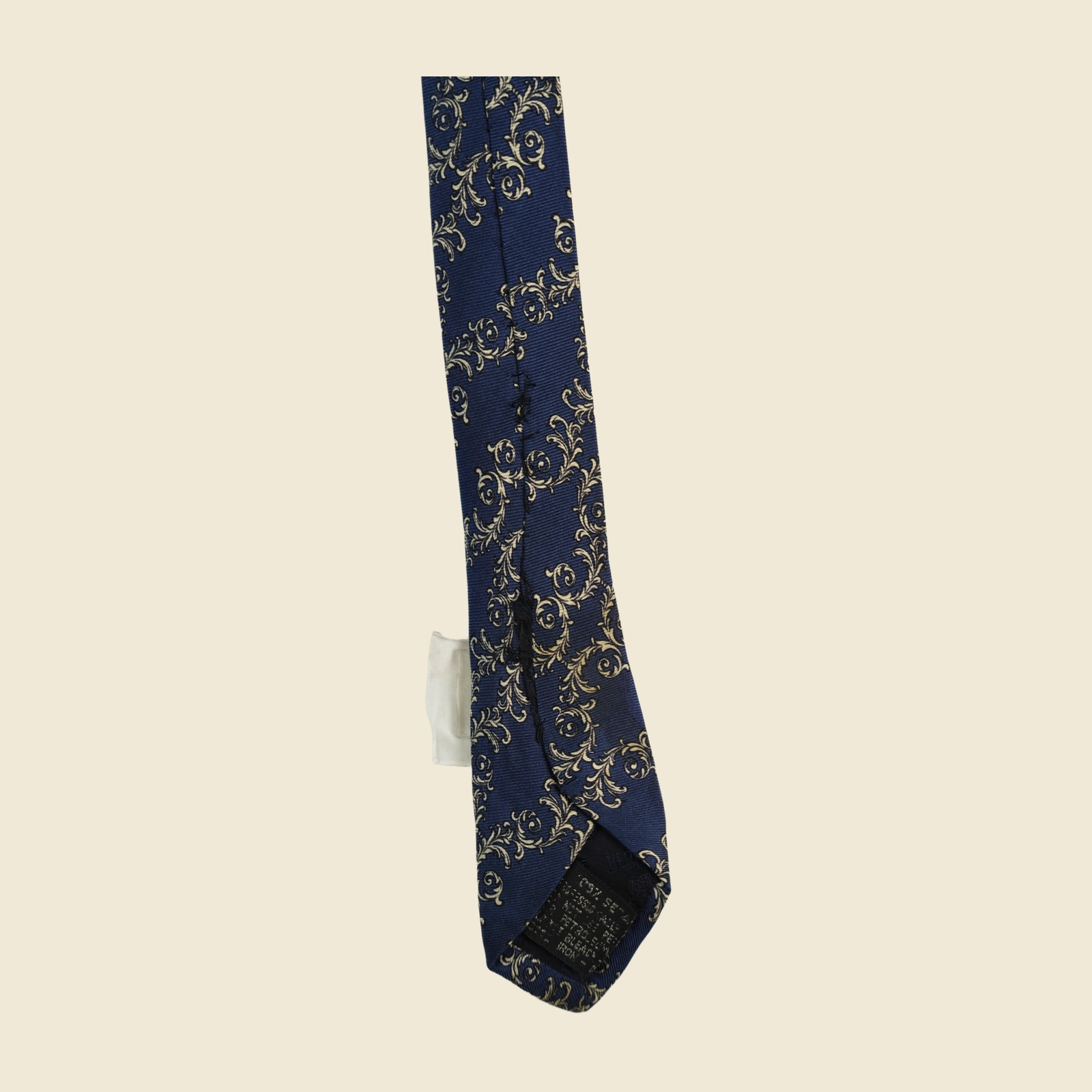 Cravatta Gianni Versace in seta blu navy con tralci d'acanto e volute avorio-oro a fasce diagonali, vista intera in posa piatta — vista 3