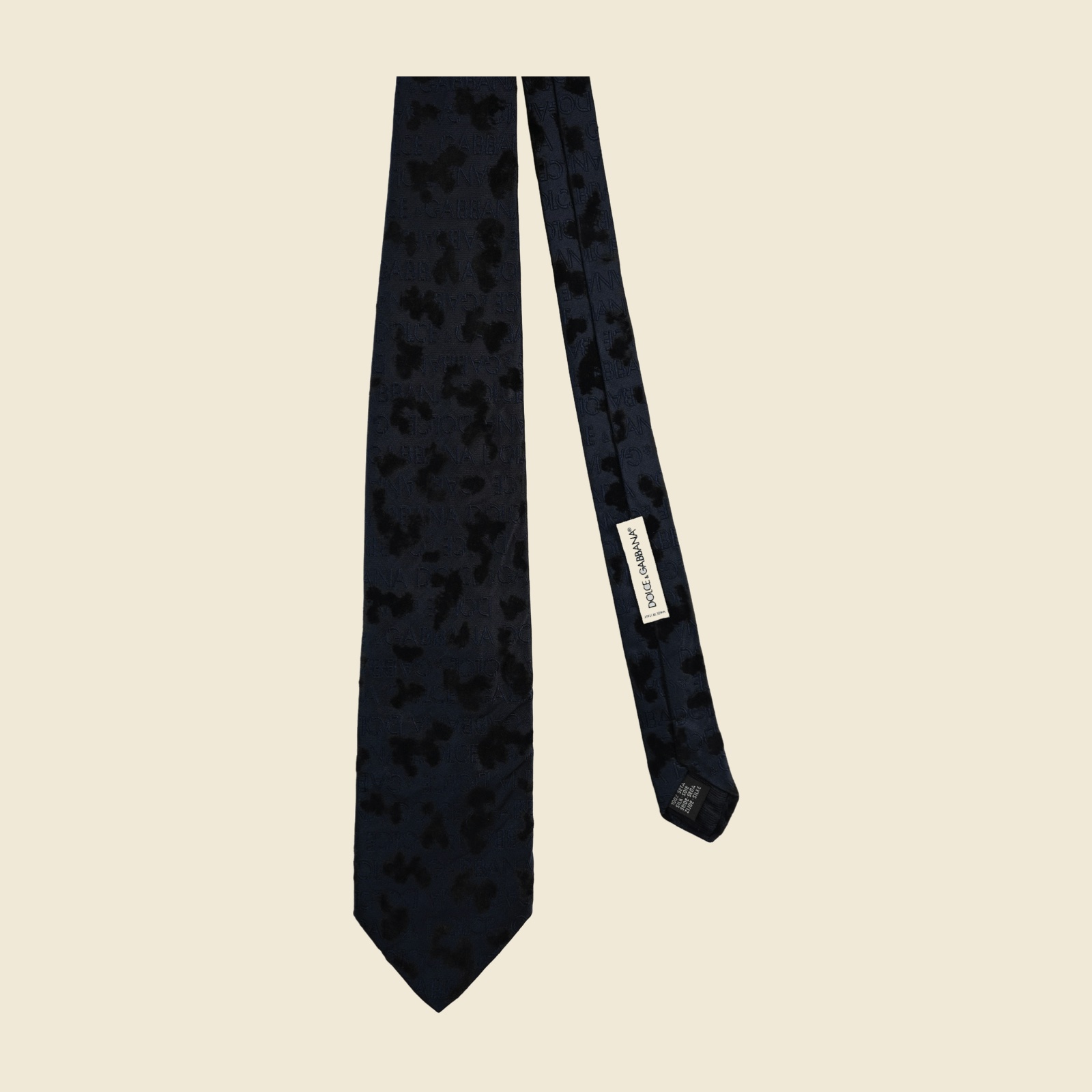 Cravatta Dolce & Gabbana in seta blu notte con macchie di velluto nero in rilievo su fondo jacquard, distesa su fondo neutro — vista 2