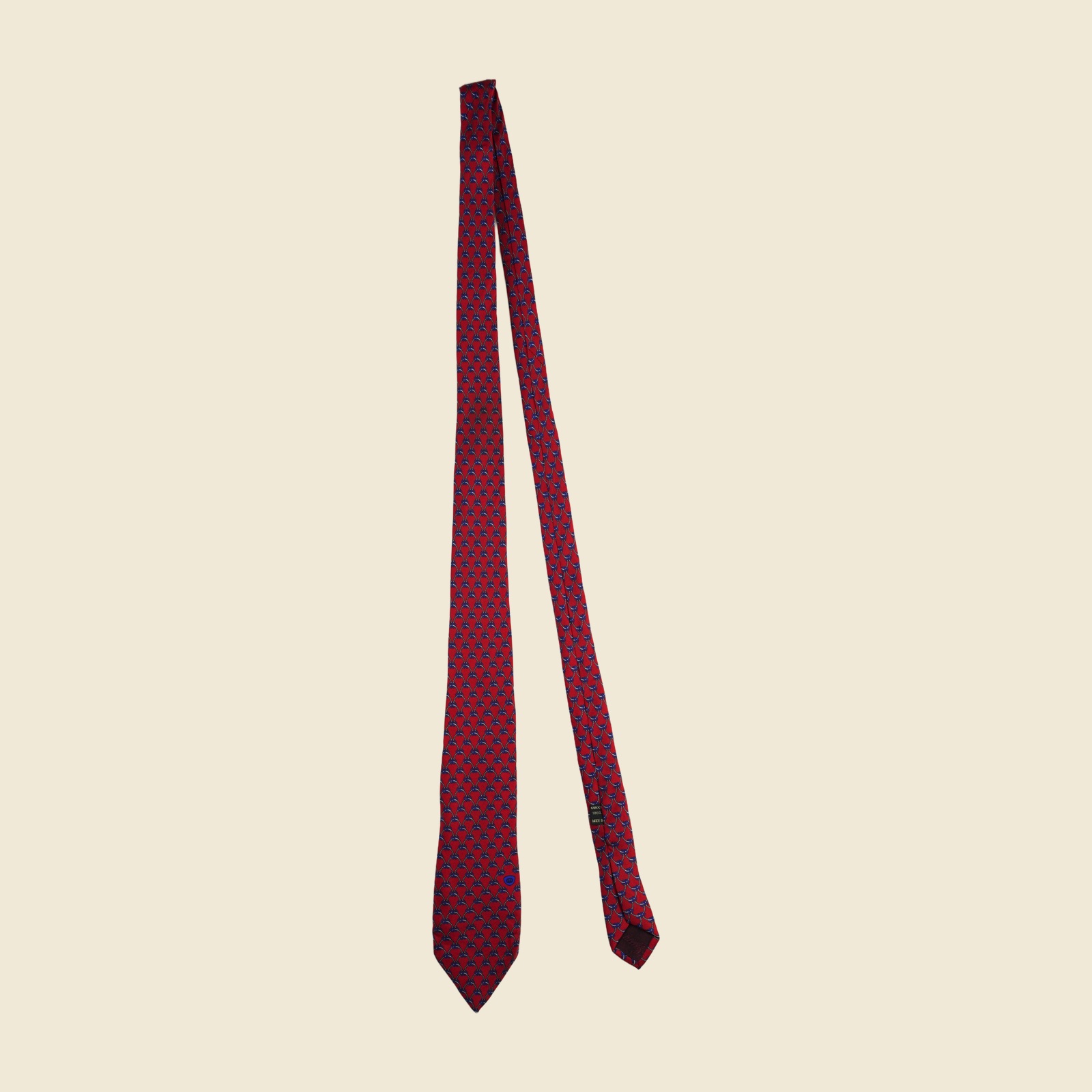 Cravatta Gucci a reticolo di corde e catenelle annodate, grigio-argento e blu su fondo rosso, con medaglione ovale blu con stemma verso la punta larga — vista 2