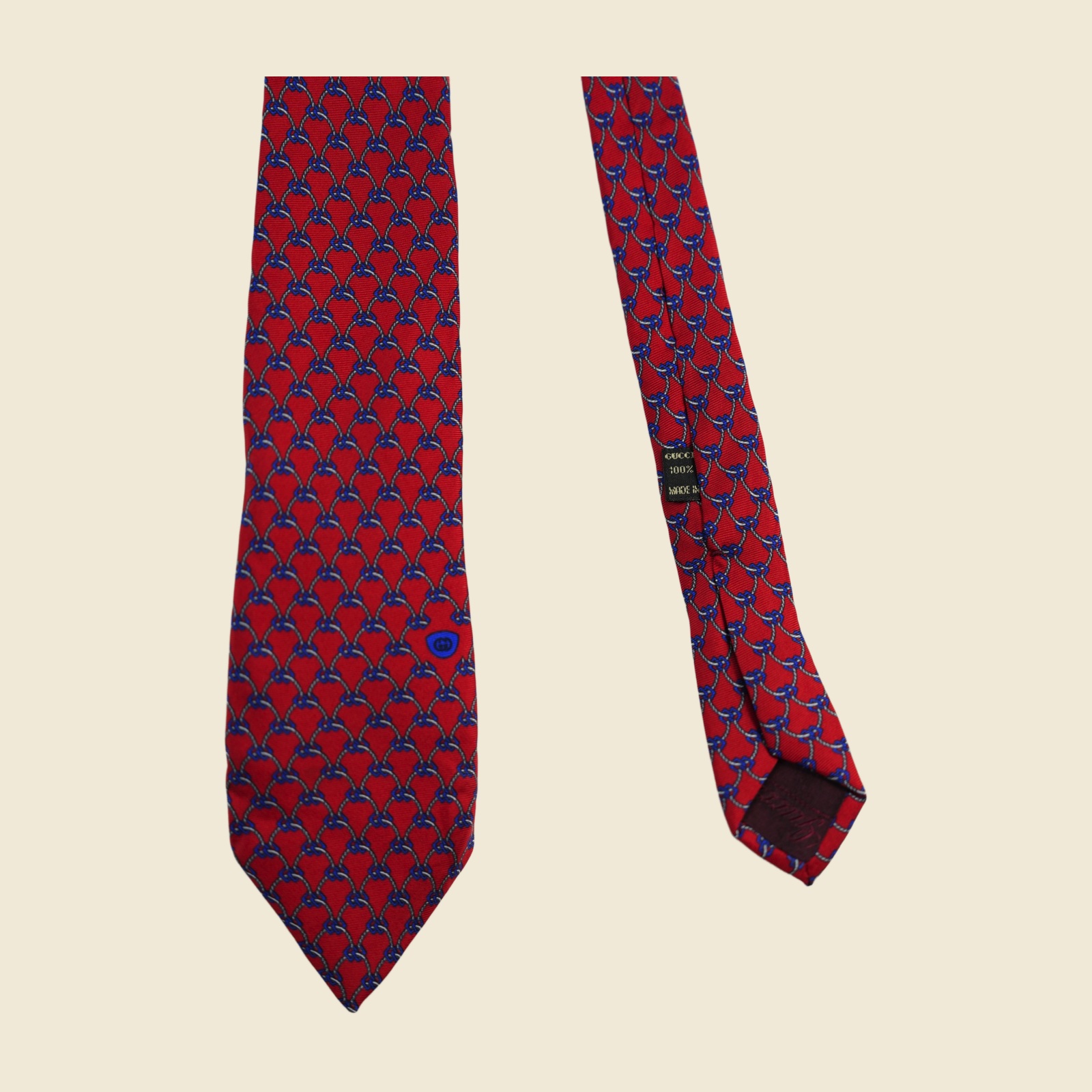 Cravatta Gucci a reticolo di corde e catenelle annodate, grigio-argento e blu su fondo rosso, con medaglione ovale blu con stemma verso la punta larga — vista 4
