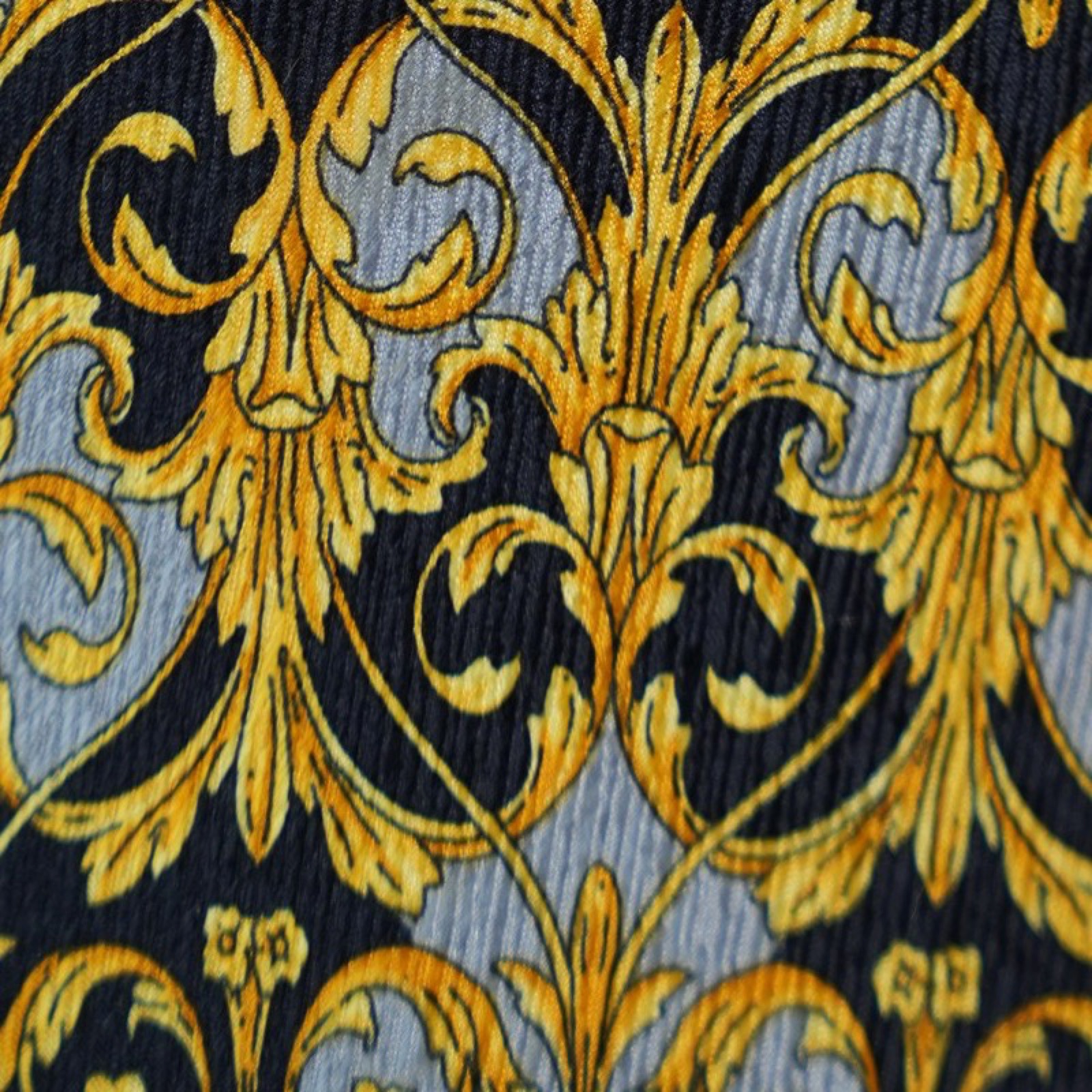 Cravatta vintage in seta nera con girali d'acanto dorati, cartigli grigio argento e mascherone solare ripetuto, su fondo neutro — vista 4