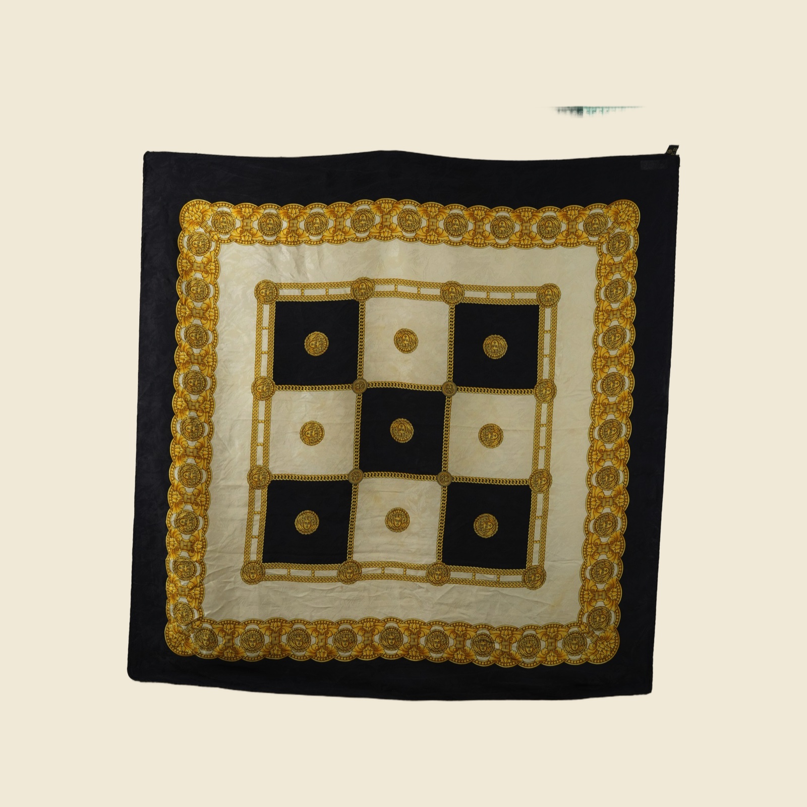 Foulard quadrato in seta disteso, scacchiera barocca di riquadri neri e avorio divisi da una catena groumette dorata, medaglioni a testa femminile coronata, campo avorio con ghirlanda a festoni e cornice nera