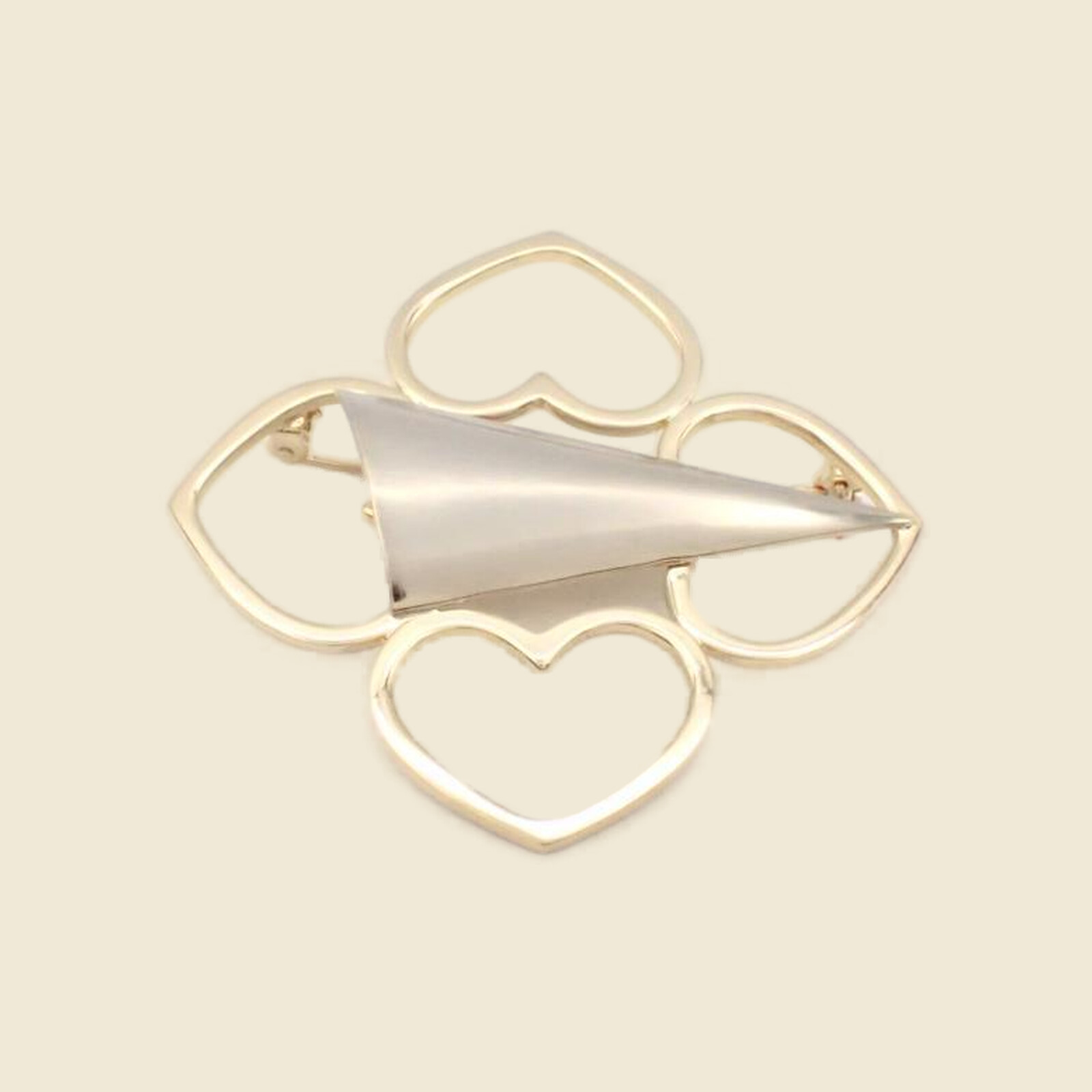 Spilla Pierre Cardin in metallo dorato a quattro cuori traforati con vela satinata argentata, su fondo neutro