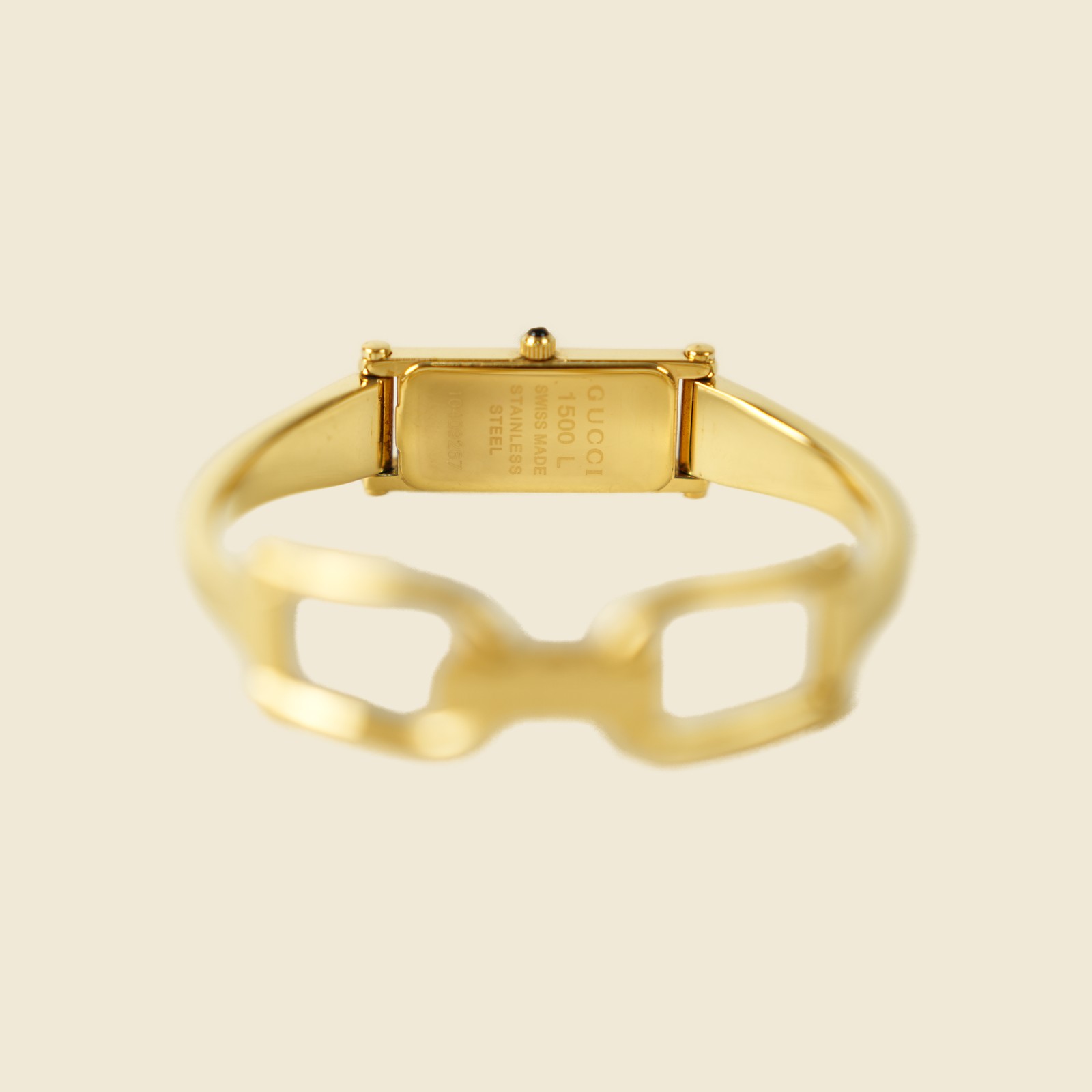 Orologio Gucci bangle in metallo dorato con morsetto sul bracciale e quadrante rettangolare, vista frontale su fondo neutro