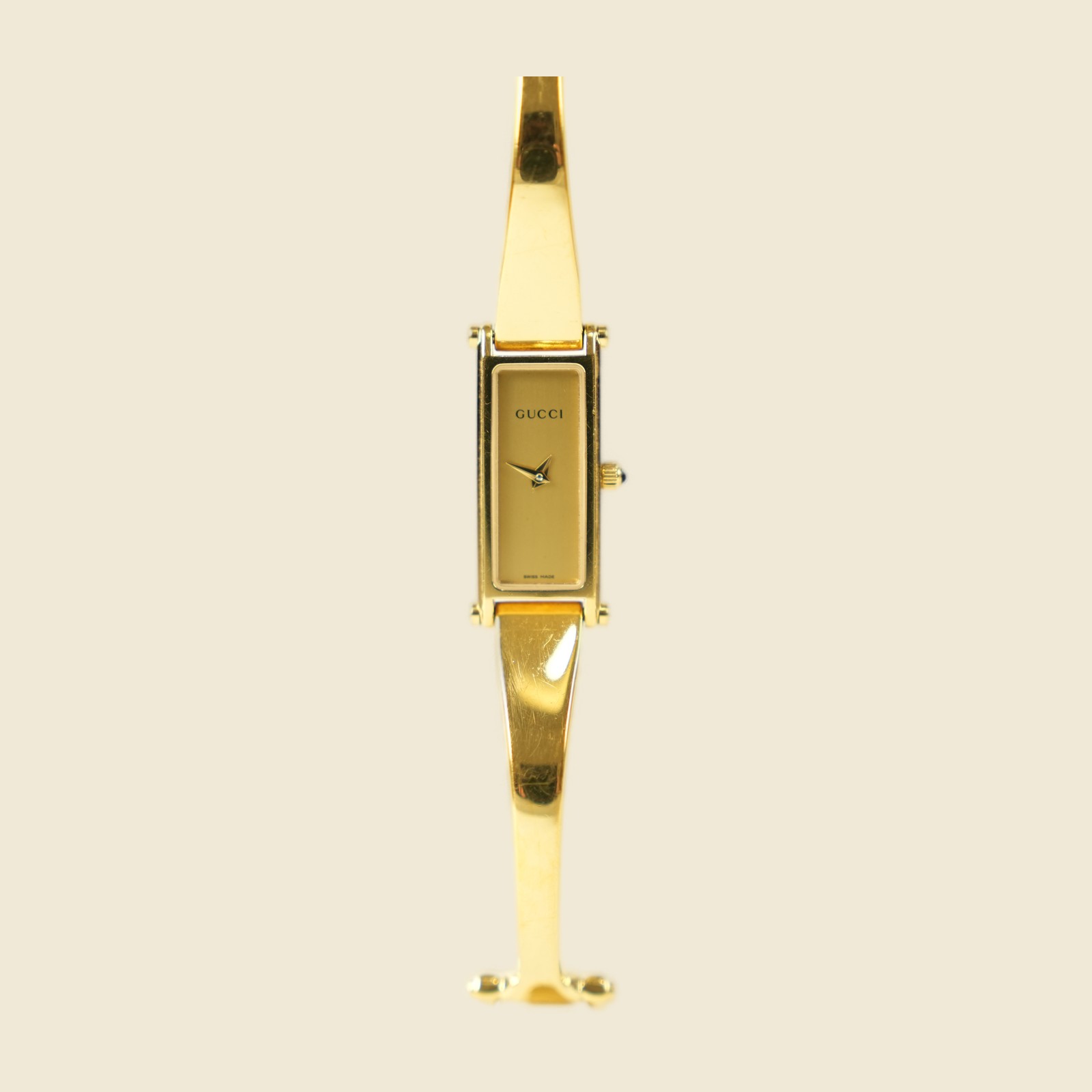 Orologio Gucci bangle in metallo dorato con morsetto sul bracciale e quadrante rettangolare, vista frontale su fondo neutro — vista 3