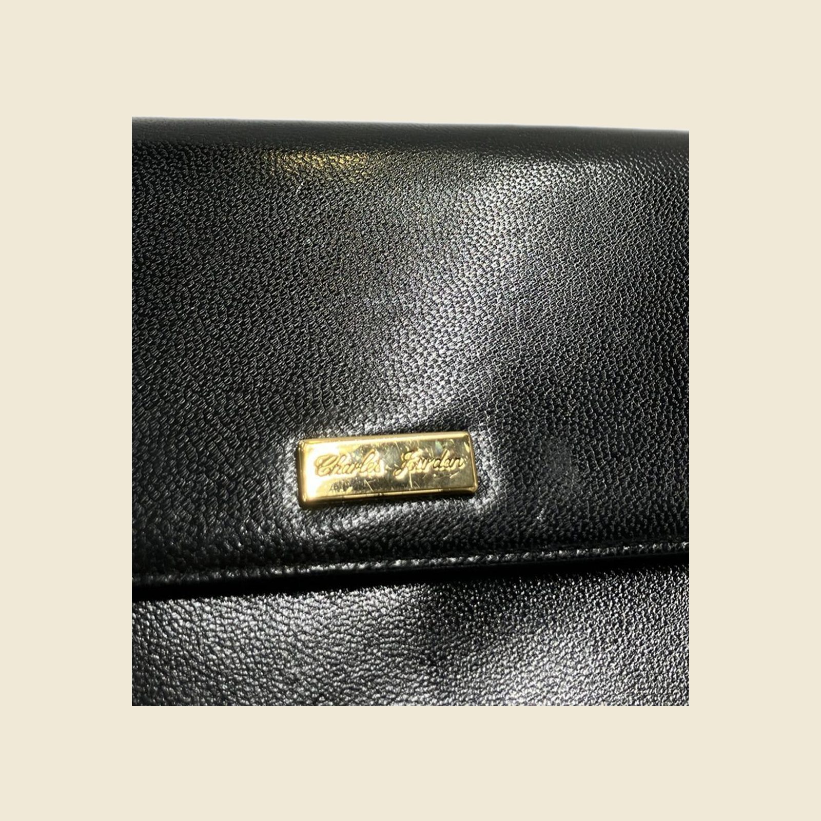 Borsa a spalla in pelle nera con patta, placchetta dorata e tracolla a catena, vista frontale su fondo bianco — vista 3